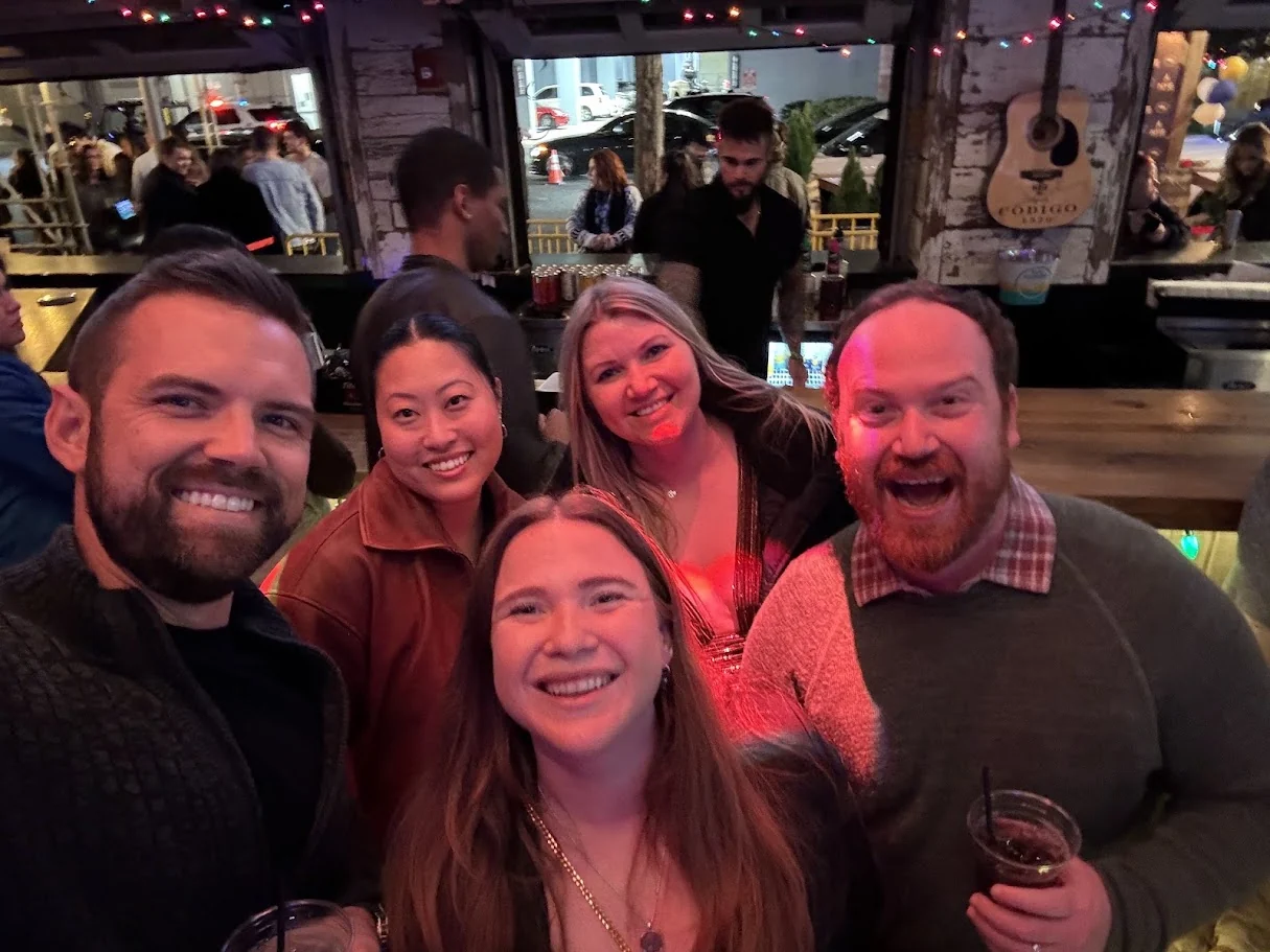 Gem and Bill out with friends — drinks up, everyone mid-laugh